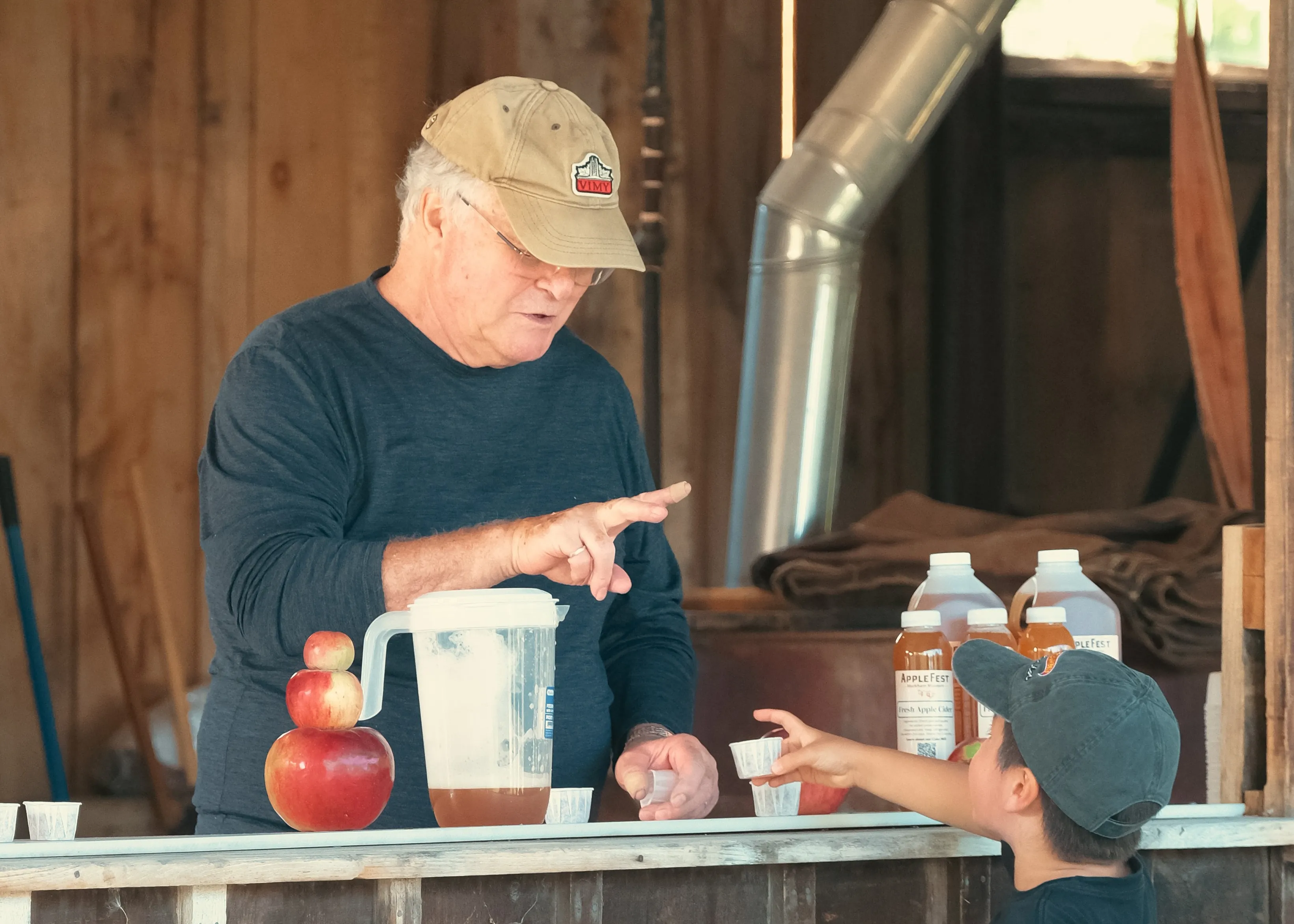 Person serving apple cider to child.